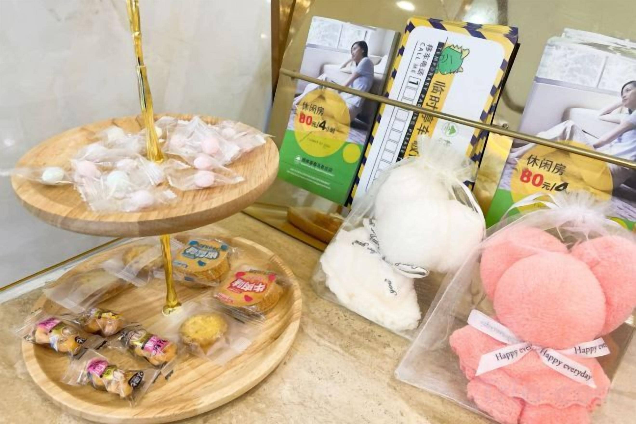 A display of various packaged snacks and desserts, including pink mochi, on a counter.
