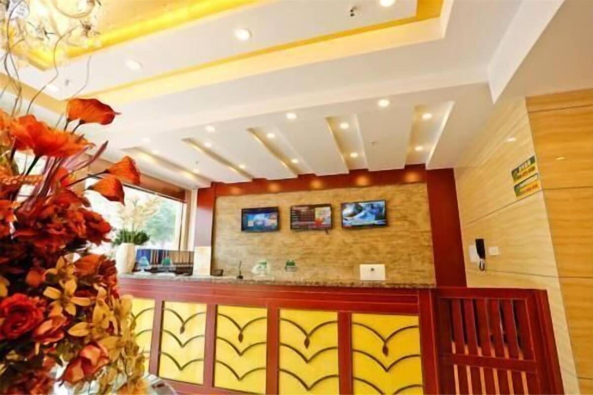 A reception desk with a modern design, a mounted television, and a decorative plant arrangement.