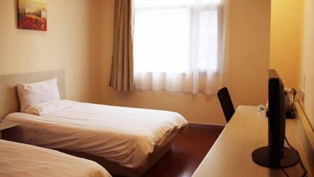 Quarto de hotel com duas camas, uma escrivaninha e uma televisão.