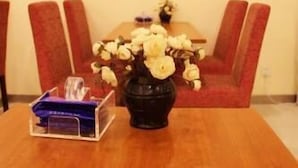 Uma mesa de jantar com um vaso de flores, um copo e uma caixa roxa.