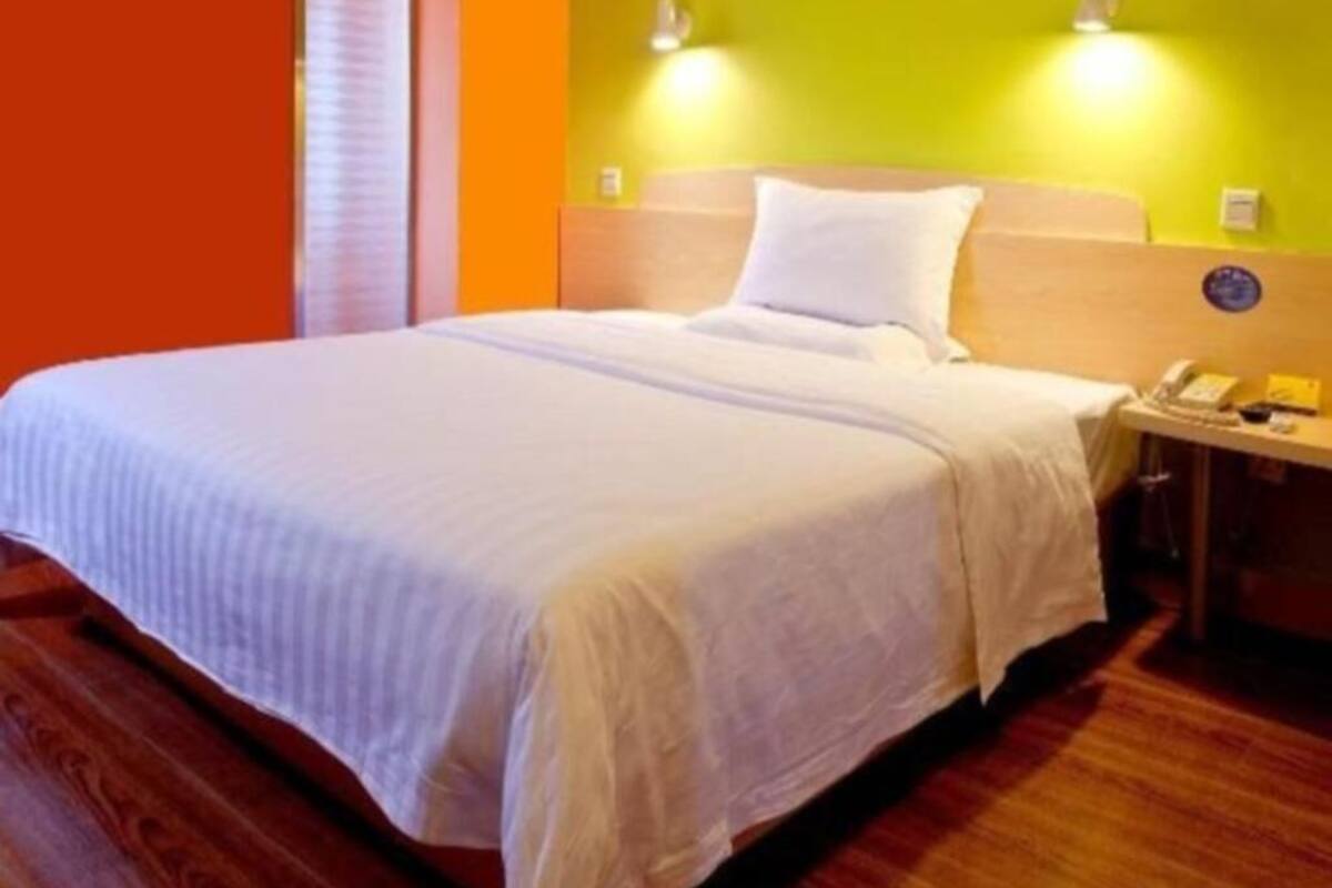 A hotel room with a bed, a nightstand, and a wall-mounted telephone.