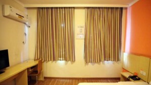 Ein Hotelzimmer mit Bett, Schreibtisch, Stuhl und Vorhängen.