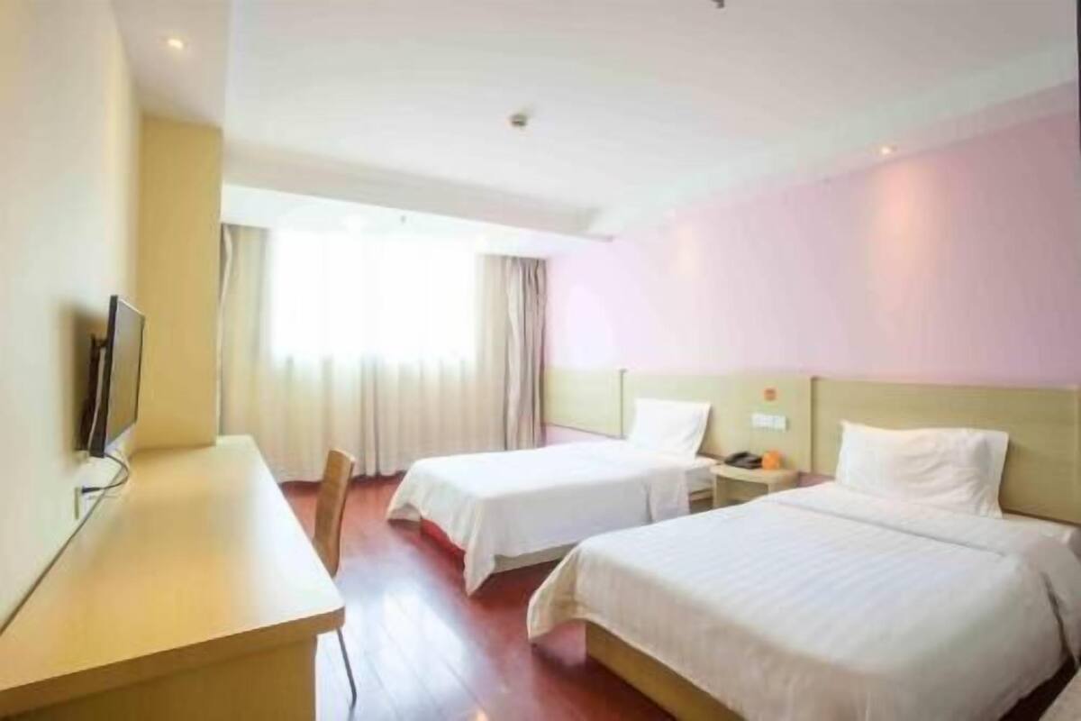 A hotel room with two beds, a desk, and a television.