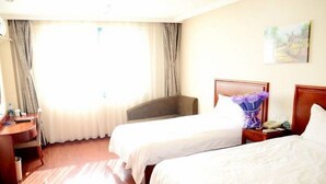 Quarto de hotel com duas camas, uma escrivaninha e uma janela com cortinas.
