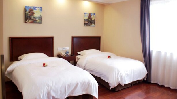A hotel room with two beds, a nightstand, and two paintings on the wall.