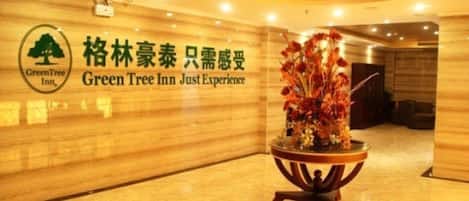 A lobby with a wooden wall, a Green Tree Inn sign, and a potted plant.
