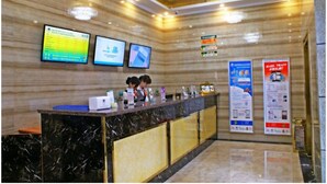 A reception desk with digital displays, a marble counter, and informational posters.