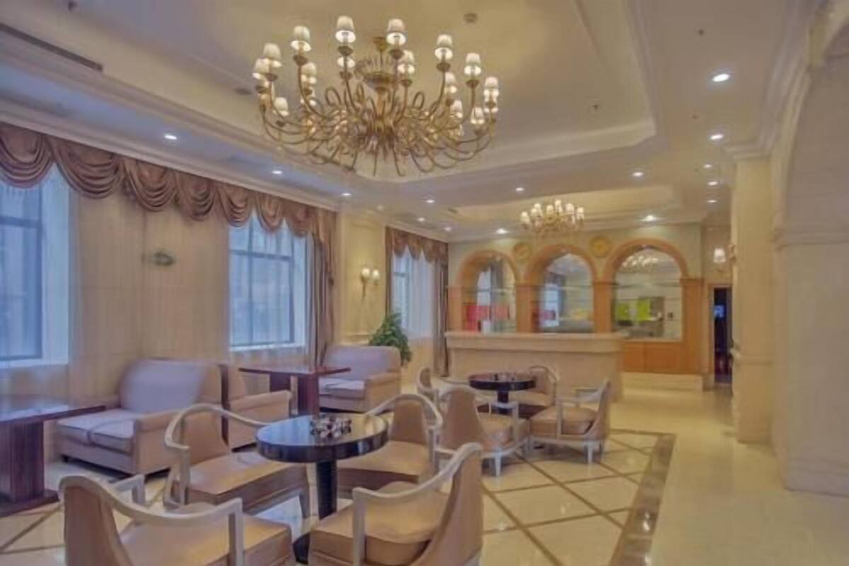 En hotellobby med en lysekrone, siddeområder og en receptionsdisk.