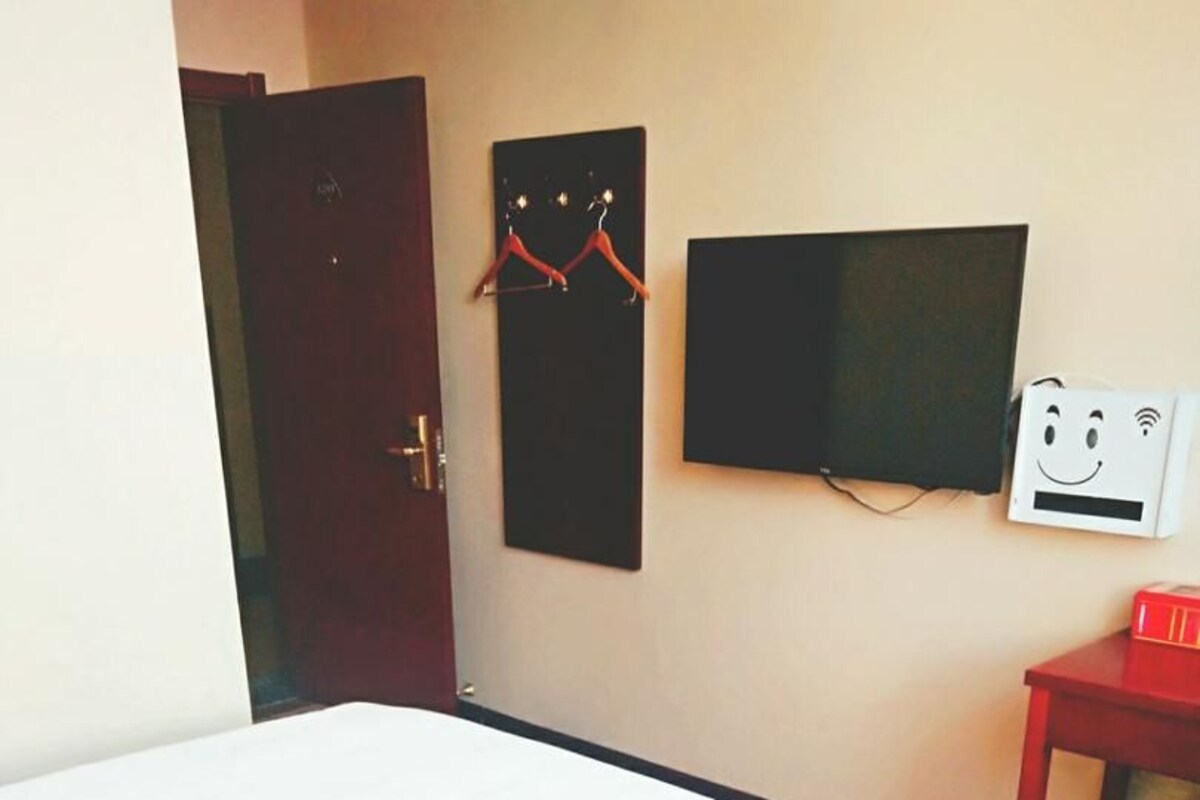 Ein Hotelzimmer mit einem Bett, einem Fernseher, einem roten Tisch und einem Mülleimer.