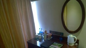 A hotel room with a wooden desk, a mirror, a white kettle, and a window with curtains. - Greentree Inn Express (Nanjing)