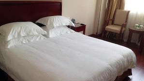 A neatly made bed with white linens in a hotel room. - Greentree Inn Express (Nanjing)