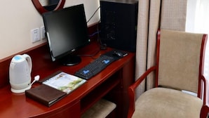 A hotel room with a wooden desk, a computer setup, a chair, a kettle, and a window with curtains. - Green Tree Inns Hotel (Beijing)