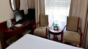 A hotel room with a bed, a desk with a computer, two chairs, a small table with a bottle, and a window with curtains. - Green Tree Inns Hotel (Beijing)