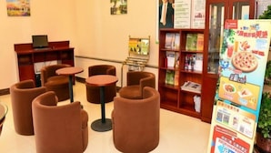 A hotel lobby with round tables, a bookshelf, and a poster. - Green Tree Inns Hotel (Beijing)