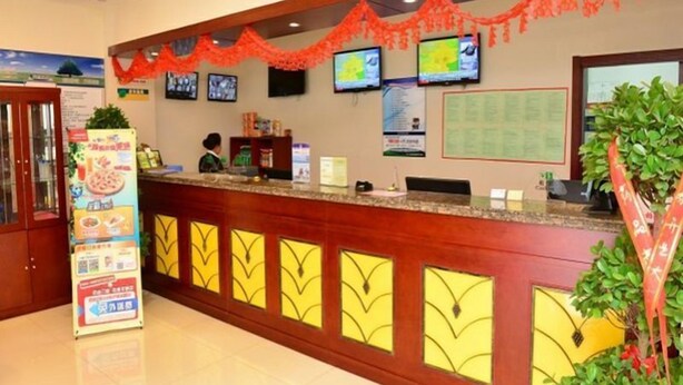 A hotel reception area with a counter, multiple monitors, a menu stand, and a large window. - Green Tree Inns Hotel (Beijing)