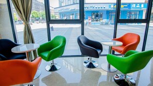 A modern interior with large windows, colorful chairs, and a view of the street outside. - Greentree (Nantong)
