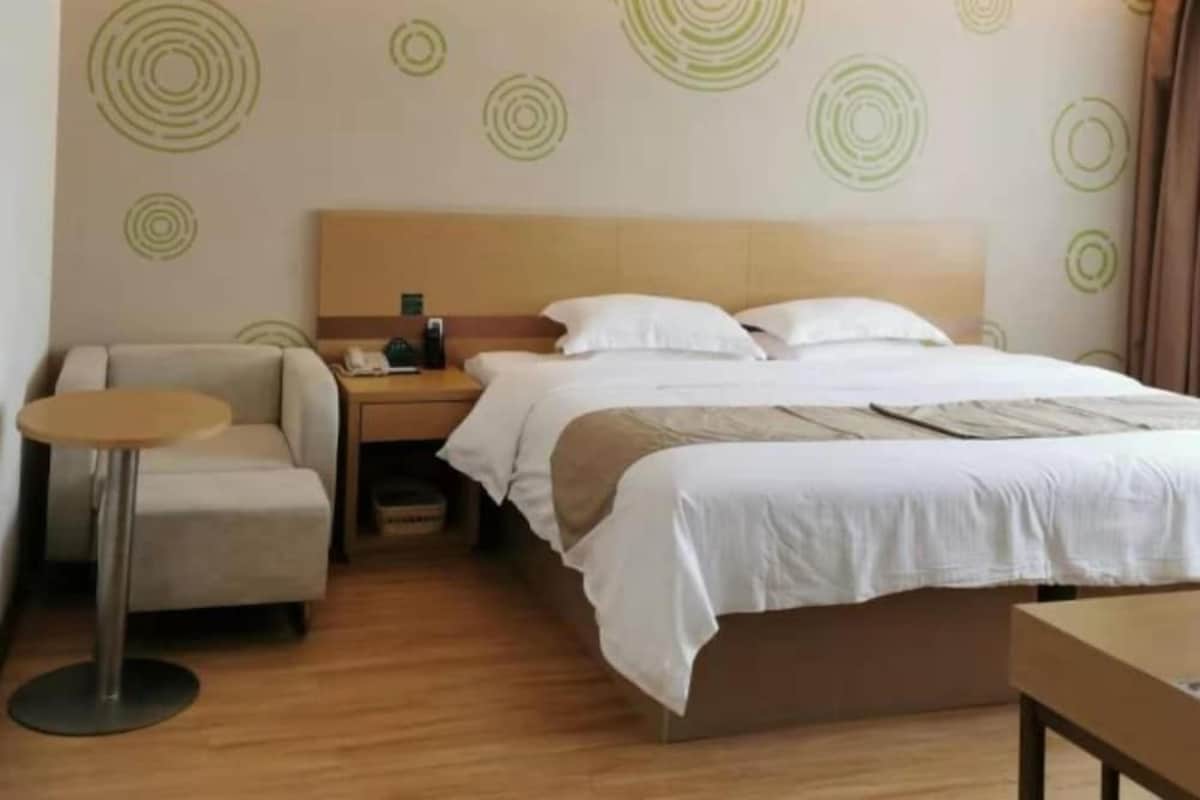 A hotel room with a bed, a nightstand, a chair, and a small table.