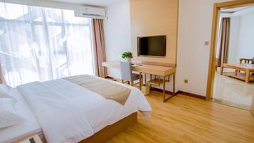 A hotel room with a bed, desk, chair, TV, and a large window.