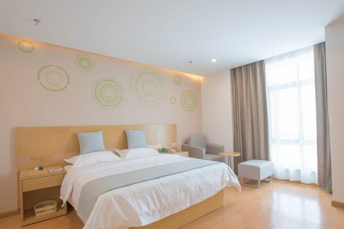 Una camera d'albergo moderna con un letto grande, comodini, una sedia e un tavolino.
