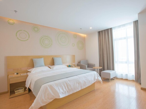 A modern hotel room with a large bed, bedside tables, a chair, and a small table. - Greentree Inn Hotel (Hefei)