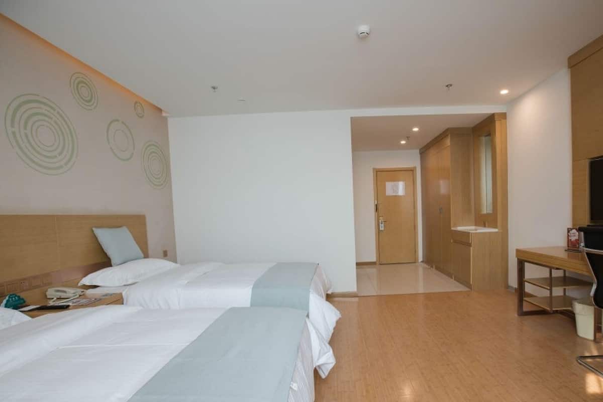 Camera d'albergo con due letti, una scrivania, uno specchio e un bagno.