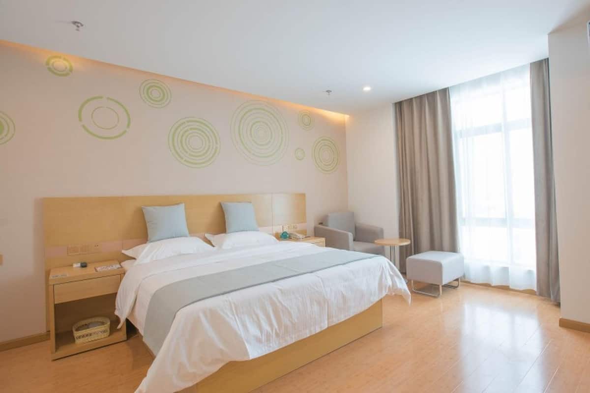 Una camera d'albergo moderna con un letto grande, comodini, una sedia, un tavolino e una finestra con tende.