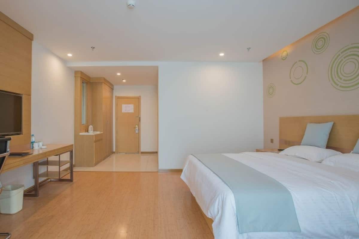Una camera d'albergo moderna con un letto, una scrivania, una televisione e un bagno.