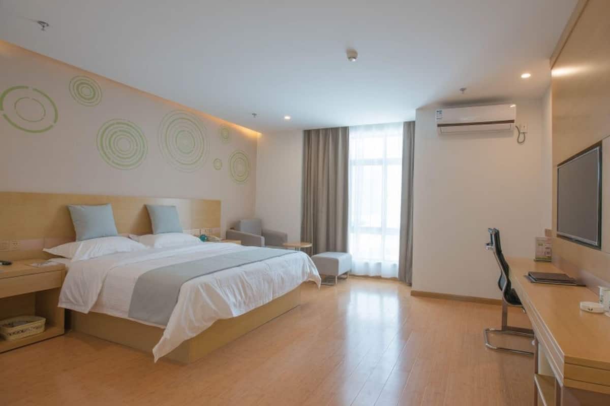 Una moderna camera d'albergo con un letto grande, comodini, una scrivania con sedia, una televisione e una finestra con tende.