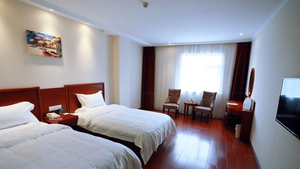 Una habitación de hotel con dos camas, televisión, escritorio y una silla.