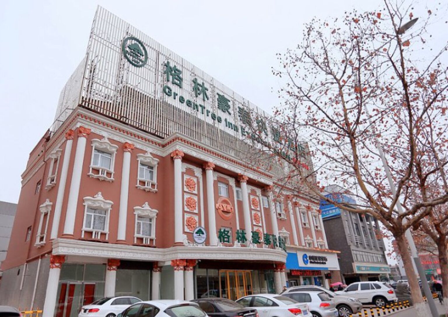 A building with a green logo and Chinese characters, indicating a hotel or similar establishment.