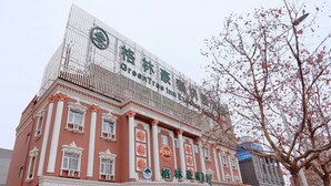 Un edificio con un logotipo verde y caracteres chinos, que indica un hotel u establecimiento similar.