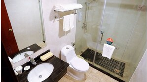 Un baño con lavamanos, inodoro y ducha con mampara de vidrio.