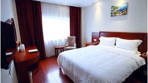 Una habitación de hotel con una cama grande, una silla, una mesita, un televisor y un cuadro en la pared.