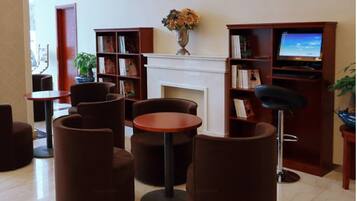 A library with bookshelves, a fireplace, and seating areas.