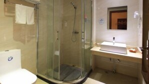 Un baño con ducha de vidrio, lavamanos blanco y retrete.
