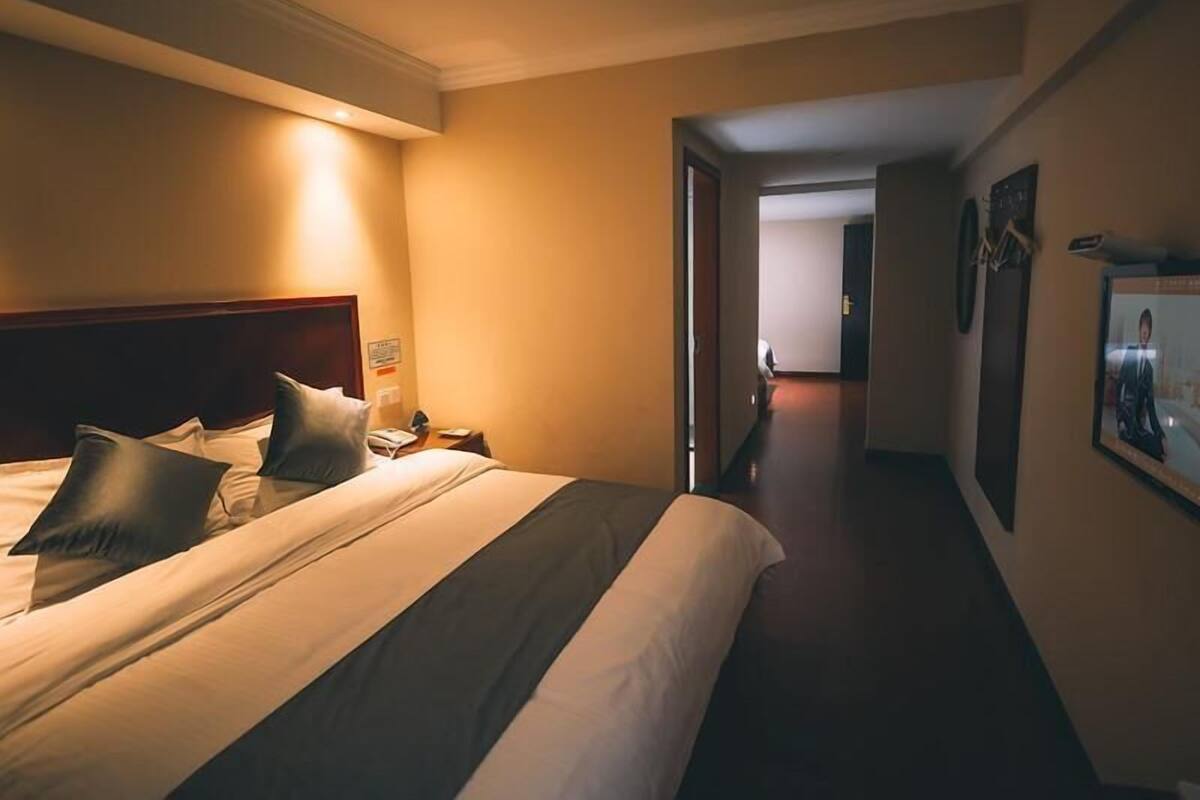 Une chambre d’hôtel avec un lit, une table de chevet et un couloir menant à une autre pièce.