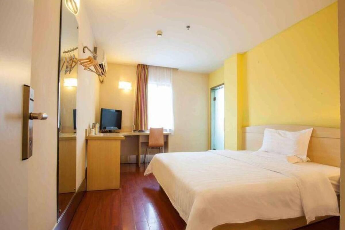 Ein Hotelzimmer mit einem Bett, einem Schreibtisch, einem Stuhl und einem Fernseher.