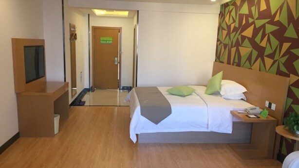 A hotel room with a bed, bedside table, TV, and a patterned wall. - Vatica Hotel (Xingtai)