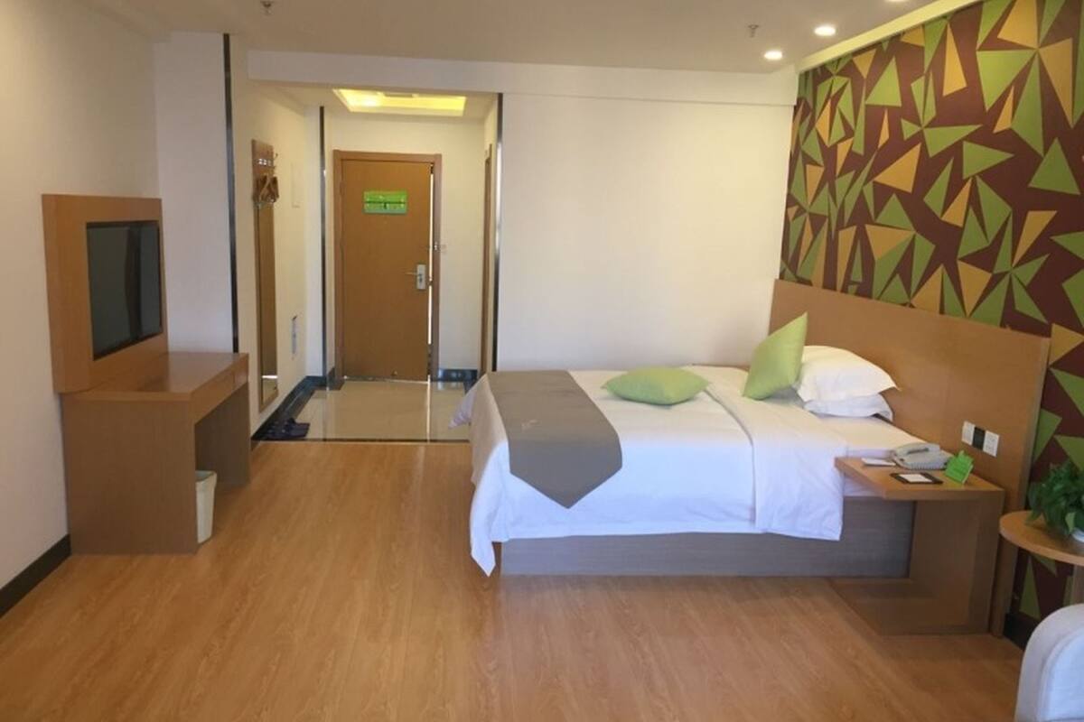 A hotel room with a bed, bedside table, TV, and a patterned wall.
