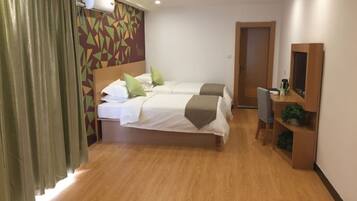 A hotel room with two beds, a wooden floor, a wall-mounted air conditioner, a door, and a small desk with a mirror.