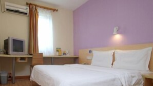 Un dormitorio con cama, escritorio con computadora, ventana con cortinas y aire acondicionado.