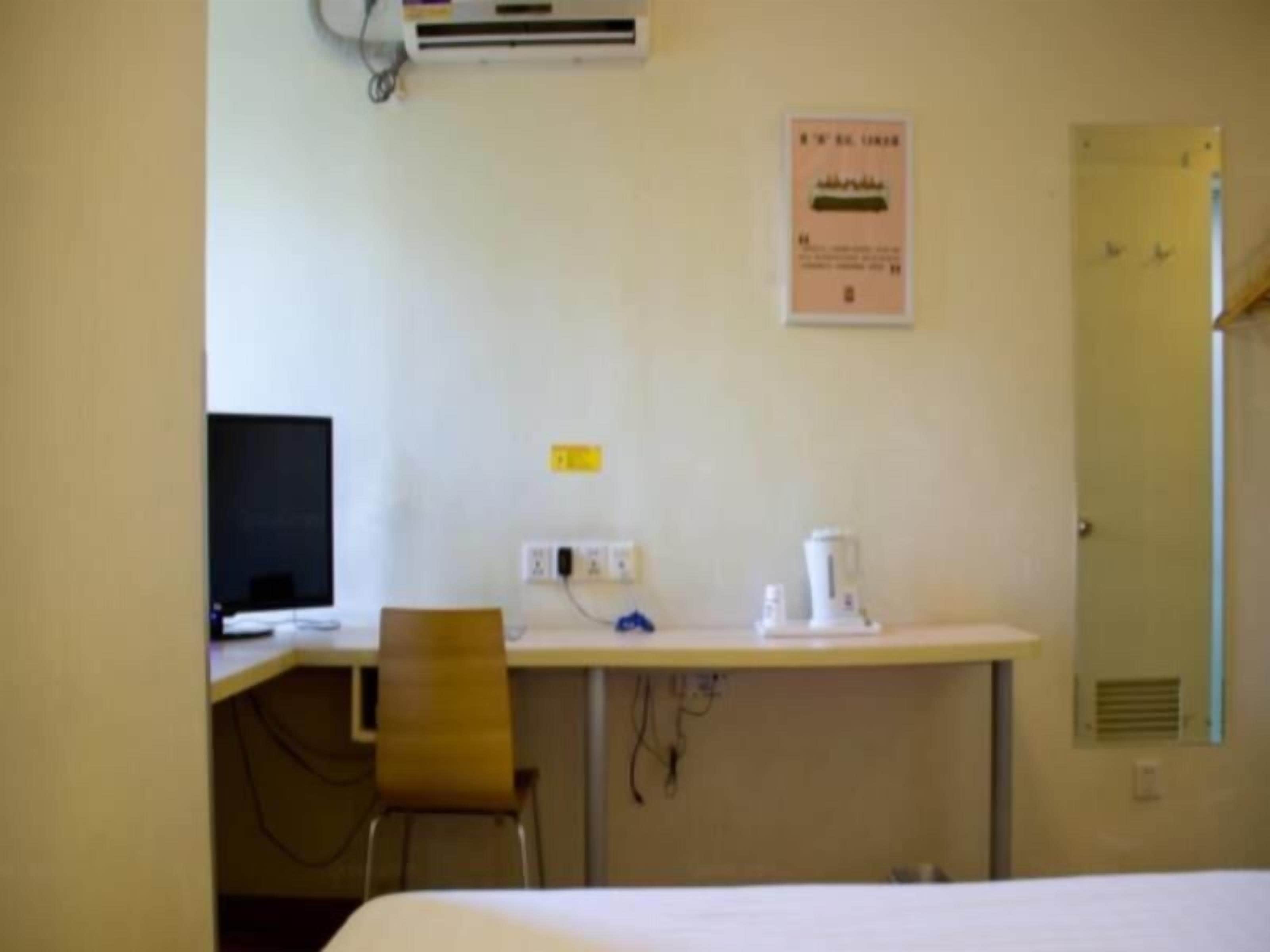 Une chambre d’hôtel équipée d’un lit, d’un bureau avec un ordinateur, d’une chaise et d’une machine à café.