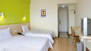 Habitación de hotel con dos camas, televisión y puerta que da a otra habitación.