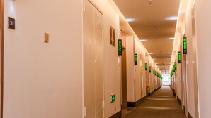 Corredor de hotel com portas identificadas por números de quarto e placas de sinalização.
