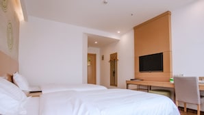 Quarto de hotel com duas camas, uma escrivaninha, uma cadeira, uma televisão e um espelho.