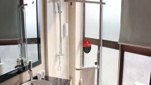 Une salle de bain moderne avec un lavabo rond, une cabine de douche en verre et un porte-serviettes.
