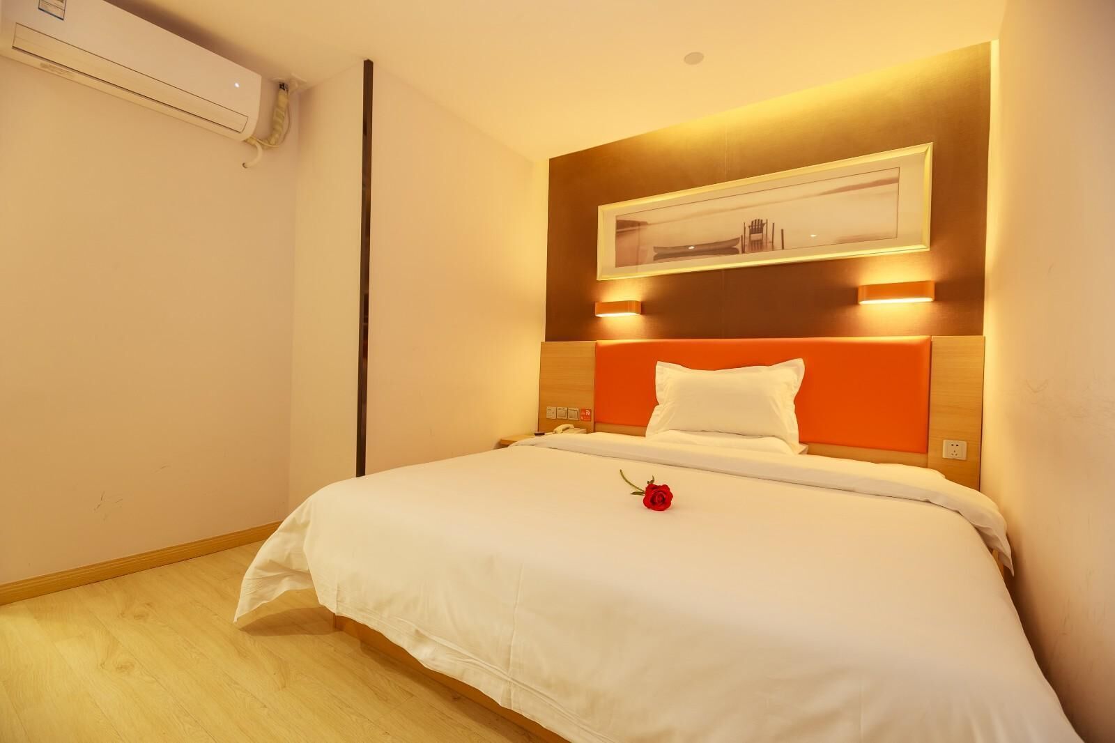 Quarto de hotel com cama, mesa de cabeceira, ar condicionado e luminária.