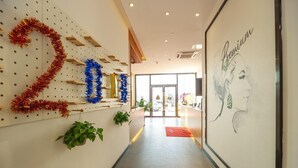 A hallway with a wall-mounted number '2019' decoration, a framed portrait, and a door leading outside. - 7 Days Premium Hotel (Chengdu)