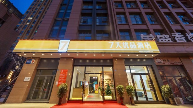 A hotel entrance with a prominent number 7 sign, a red carpet, and potted plants. - 7 Days Premium Hotel (Chengdu)