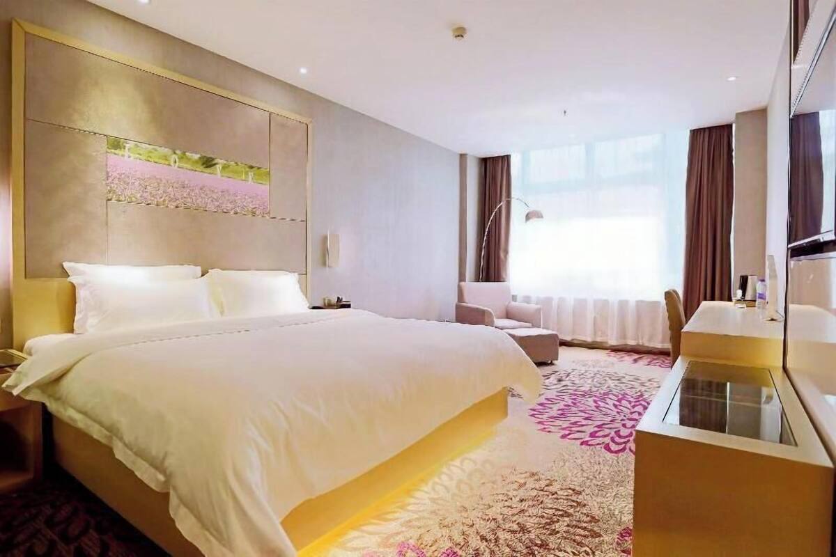Een hotelkamer met een groot bed, een bureau, een stoel en een groot raam.